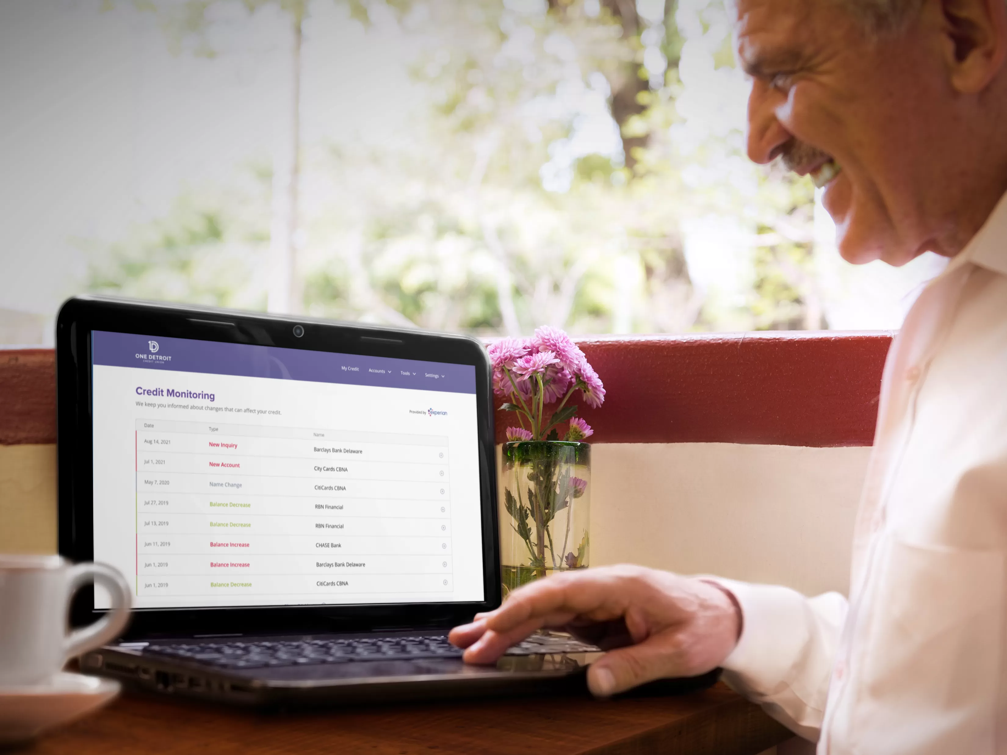 elderly man using laptop while drinking coffee at a cafe